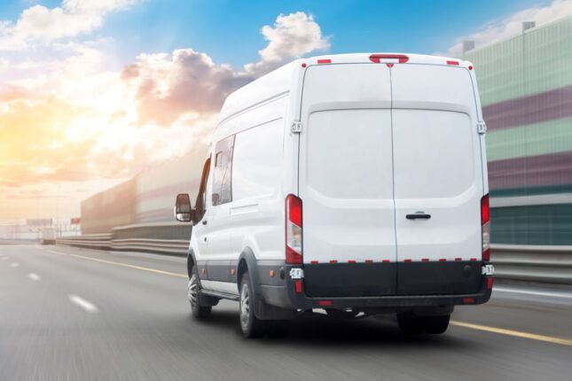 A delivery van in a fleet drives through a busy city.