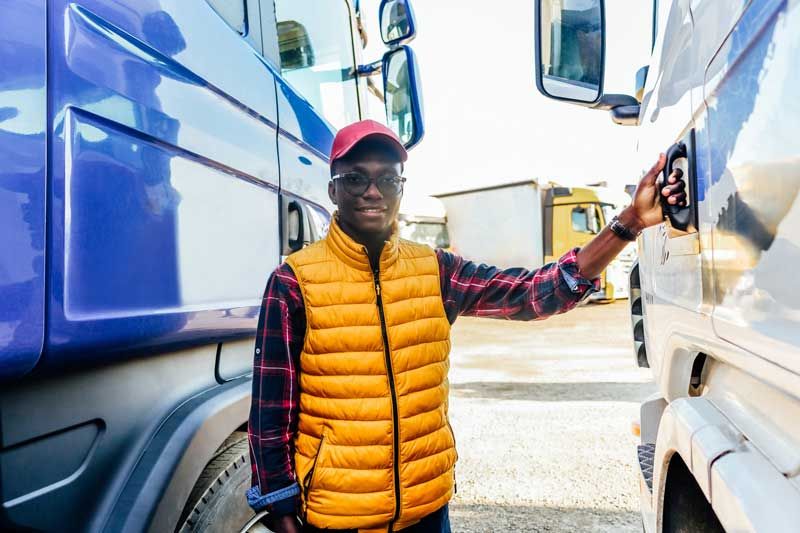 A happy truck driver prepares to get in his fleet to drive his route.