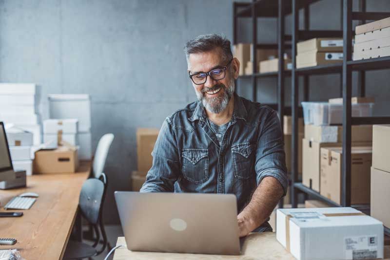A happy business owner reviews fleet card usage for easier accounting from his laptop.