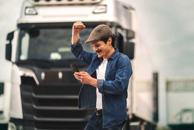 A happy trucker uses his phone to review his account used for his business fleet card.
